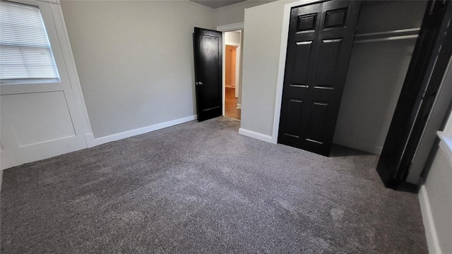 unfurnished bedroom with a closet and dark colored carpet