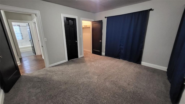 unfurnished bedroom featuring dark carpet and connected bathroom