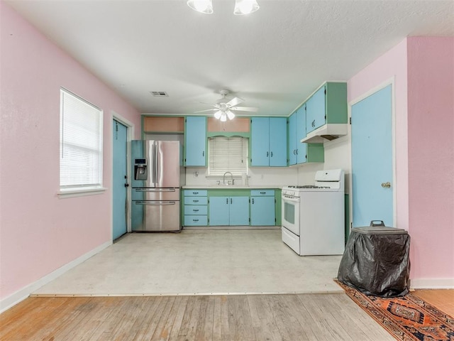 kitchen with visible vents, light countertops, under cabinet range hood, stainless steel refrigerator with ice dispenser, and gas range gas stove