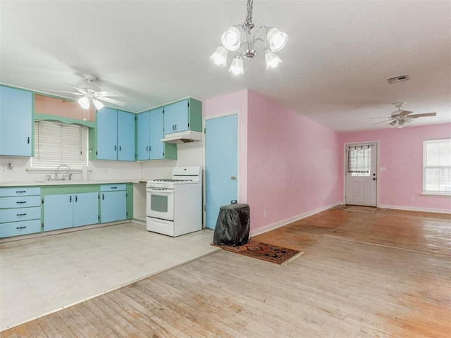 kitchen featuring visible vents, light countertops, a sink, under cabinet range hood, and white gas range oven