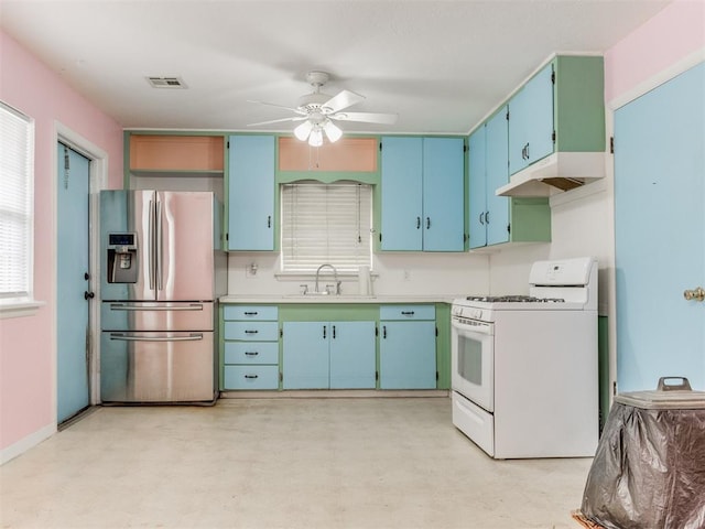 kitchen featuring white gas range oven, light countertops, under cabinet range hood, stainless steel refrigerator with ice dispenser, and a sink