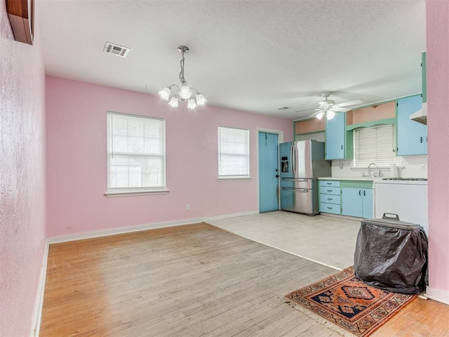 kitchen with stainless steel refrigerator with ice dispenser, visible vents, light countertops, hanging light fixtures, and wood finished floors