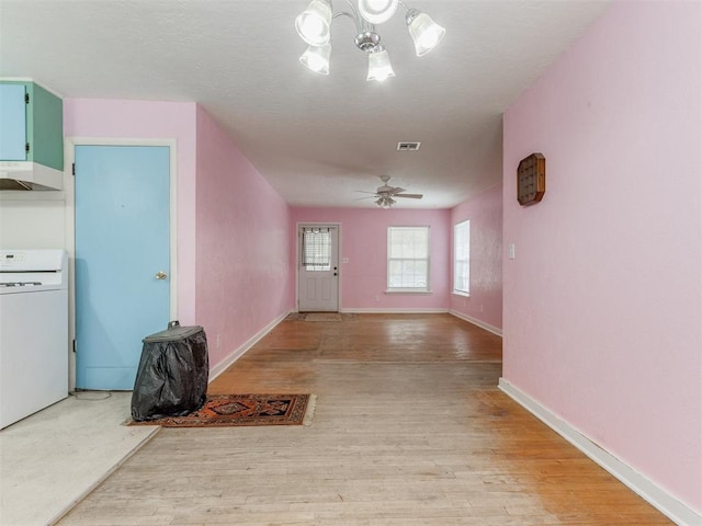 interior space featuring visible vents, ceiling fan with notable chandelier, light wood-type flooring, and washer / dryer