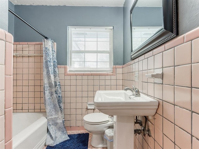 full bathroom featuring toilet, tile walls, shower / tub combo with curtain, and wainscoting