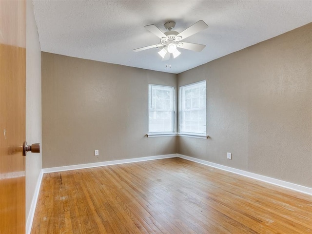 empty room featuring ceiling fan, light wood-style flooring, and baseboards