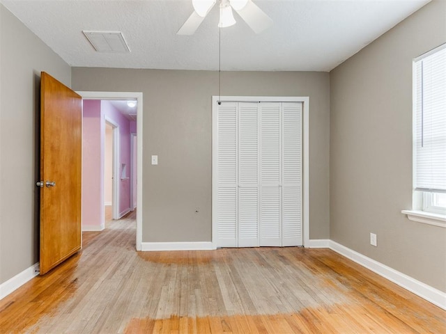 unfurnished bedroom featuring light wood finished floors, baseboards, visible vents, and a closet