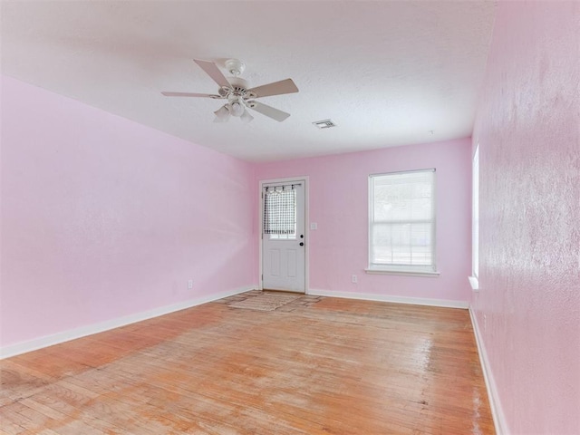 unfurnished room with light wood finished floors, baseboards, visible vents, and a ceiling fan