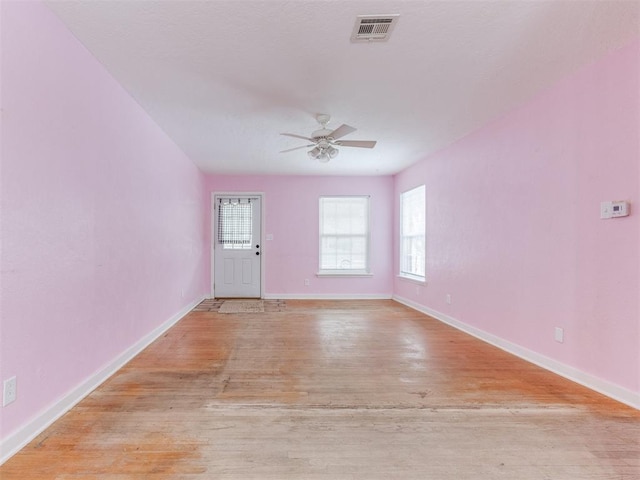 empty room featuring light wood-style floors, baseboards, visible vents, and a ceiling fan