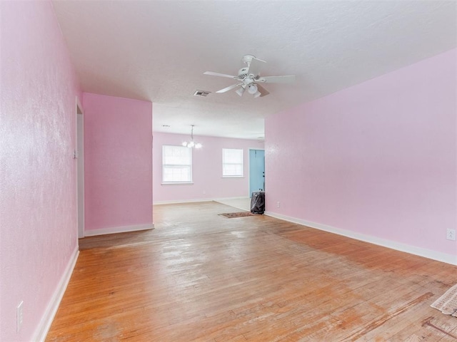 spare room with light wood-style floors, baseboards, visible vents, and ceiling fan with notable chandelier