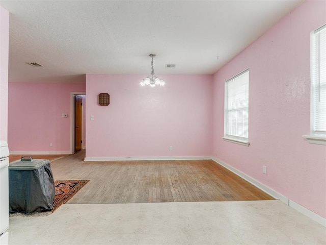 interior space with a chandelier, light wood-type flooring, visible vents, and baseboards