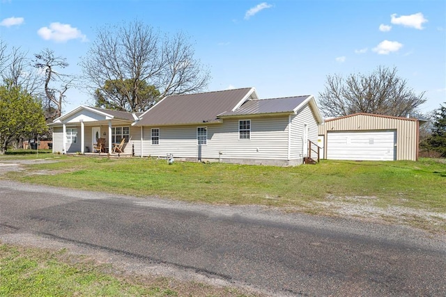 ranch-style house featuring a porch, a garage, an outbuilding, and a front yard