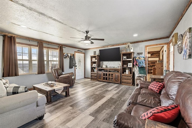 living room featuring ceiling fan, hardwood / wood-style floors, a textured ceiling, and ornamental molding