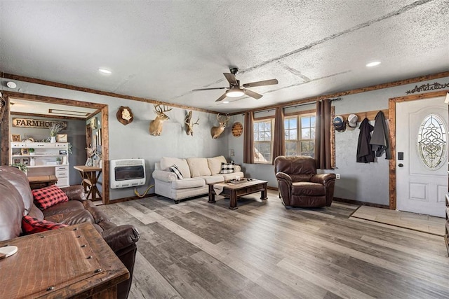 living room with a textured ceiling, heating unit, hardwood / wood-style flooring, and ceiling fan