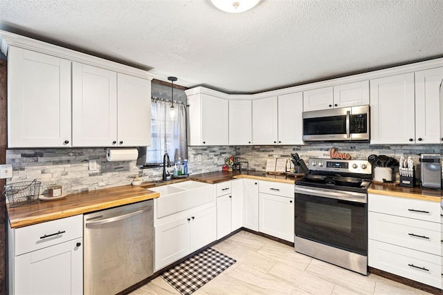 kitchen featuring wooden counters, appliances with stainless steel finishes, sink, decorative light fixtures, and white cabinets