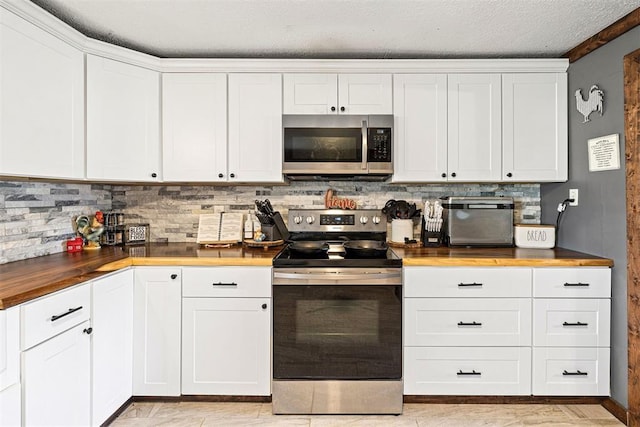 kitchen featuring backsplash, white cabinets, a textured ceiling, butcher block countertops, and stainless steel appliances