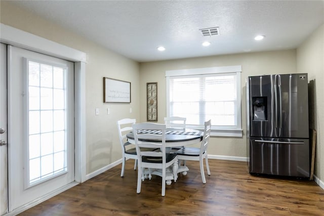 dining space with a textured ceiling, dark hardwood / wood-style floors, and a healthy amount of sunlight