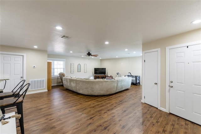 living room with ceiling fan and dark wood-type flooring