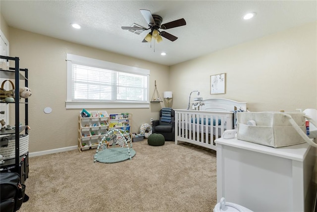 carpeted bedroom featuring a nursery area and ceiling fan