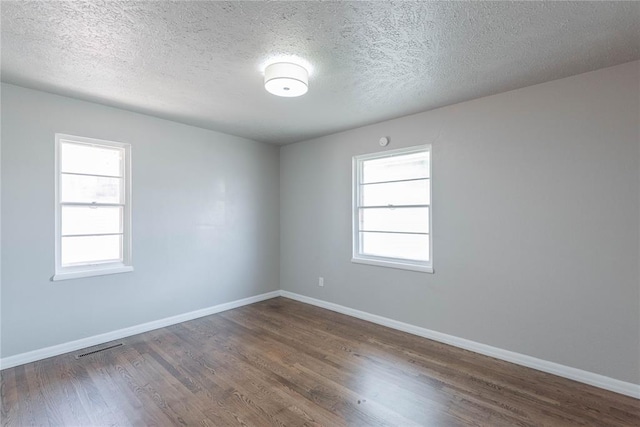 empty room with dark hardwood / wood-style flooring and a textured ceiling