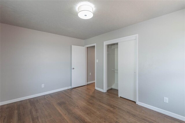 unfurnished bedroom with a textured ceiling, dark hardwood / wood-style floors, and a closet