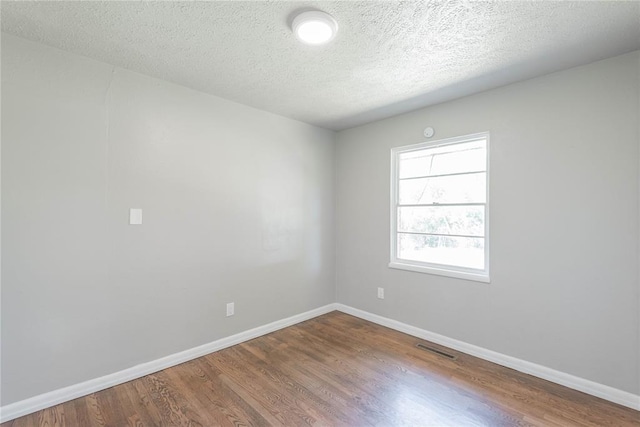 empty room featuring hardwood / wood-style flooring and a textured ceiling