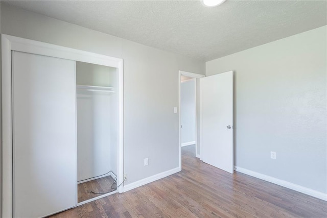 unfurnished bedroom with hardwood / wood-style flooring, a textured ceiling, and a closet