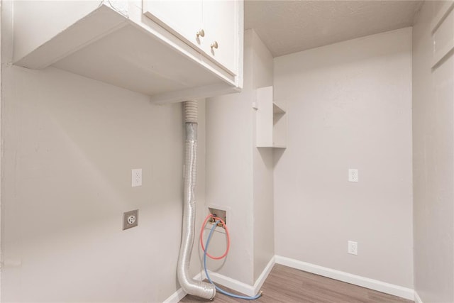 clothes washing area featuring cabinets, hookup for a washing machine, hardwood / wood-style flooring, and electric dryer hookup