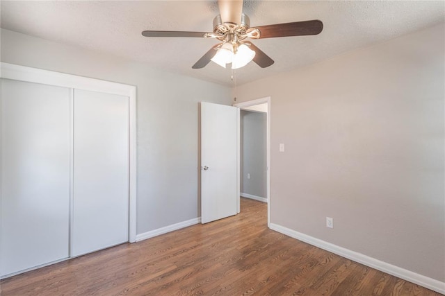 unfurnished bedroom with ceiling fan, a closet, and hardwood / wood-style flooring