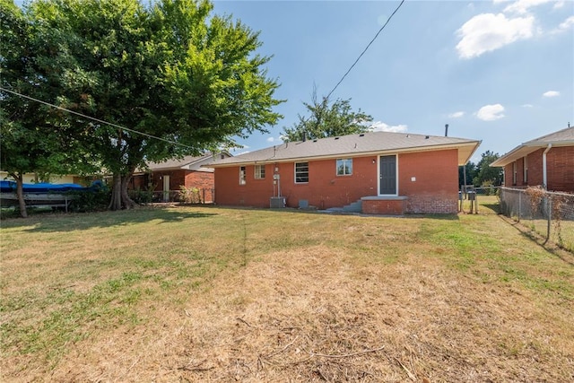 rear view of house featuring a lawn and central air condition unit