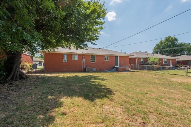 rear view of property with a yard and central air condition unit