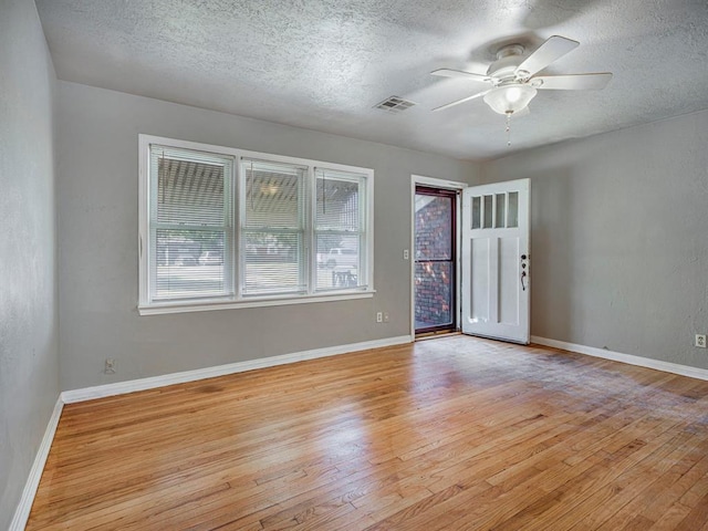 empty room with a textured ceiling, light hardwood / wood-style floors, and ceiling fan