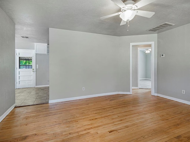 unfurnished room featuring a textured ceiling, light wood-type flooring, and ceiling fan