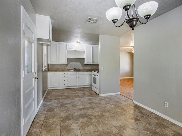 kitchen featuring white range with gas cooktop, sink, white cabinets, and an inviting chandelier