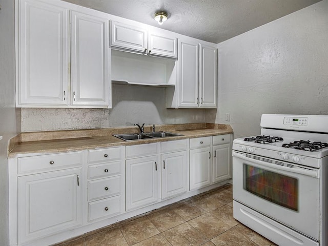 kitchen with sink, light tile patterned flooring, a textured ceiling, white cabinets, and white gas range oven