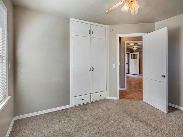 unfurnished bedroom with carpet flooring, ceiling fan, a closet, and a textured ceiling