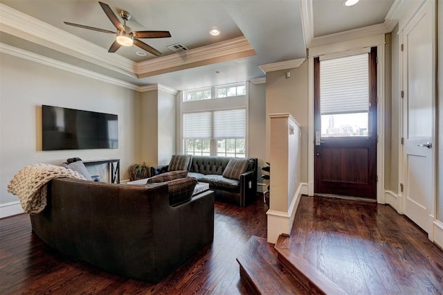 living room with dark hardwood / wood-style flooring, a tray ceiling, ceiling fan, and ornamental molding