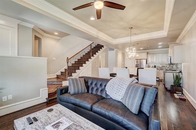 living room featuring a raised ceiling, ceiling fan with notable chandelier, dark hardwood / wood-style floors, and ornamental molding