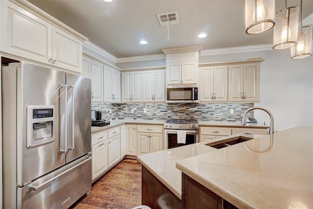 kitchen featuring backsplash, dark wood-type flooring, sink, hanging light fixtures, and premium appliances