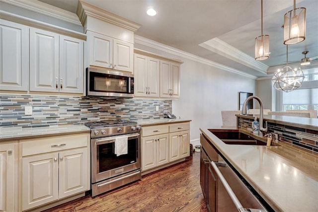 kitchen featuring backsplash, sink, hanging light fixtures, wood-type flooring, and stainless steel appliances