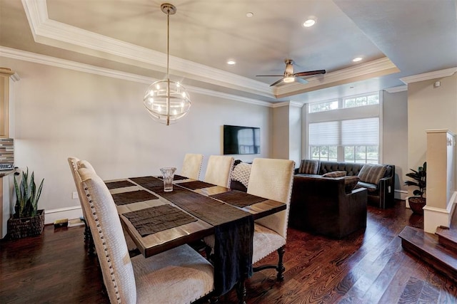 dining area with dark hardwood / wood-style floors, ornamental molding, ceiling fan with notable chandelier, and a tray ceiling