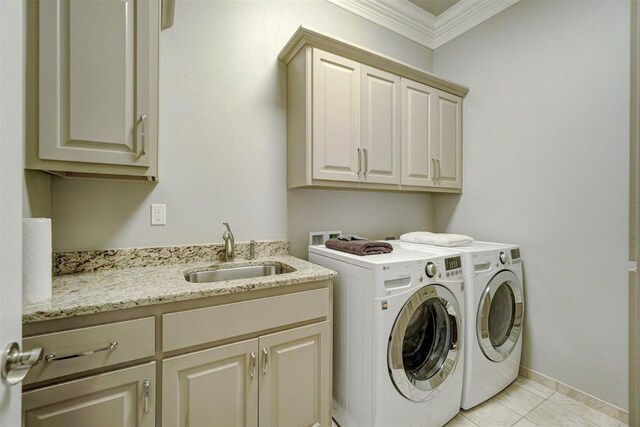 clothes washing area featuring cabinets, ornamental molding, sink, light tile patterned floors, and separate washer and dryer