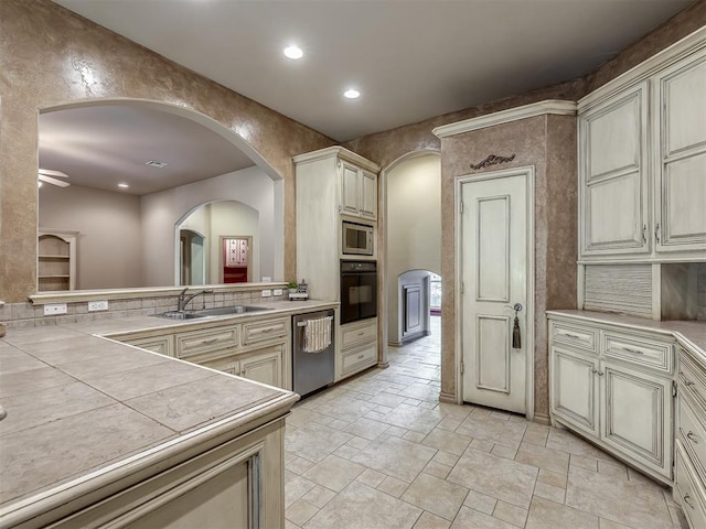 kitchen featuring tile counters, sink, cream cabinetry, and appliances with stainless steel finishes