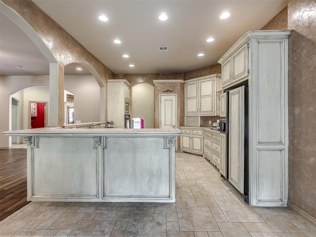 kitchen with paneled built in fridge, a kitchen breakfast bar, a center island, and cream cabinetry