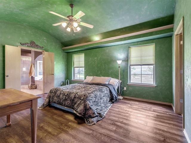 bedroom featuring hardwood / wood-style floors, vaulted ceiling, ensuite bath, and ceiling fan