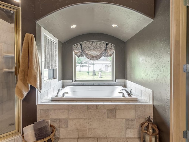 bathroom with vaulted ceiling, tile patterned flooring, plus walk in shower, and a textured ceiling