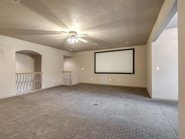 carpeted cinema with ceiling fan and a textured ceiling