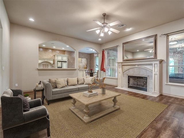 living room with a tiled fireplace, ceiling fan, hardwood / wood-style floors, and a healthy amount of sunlight