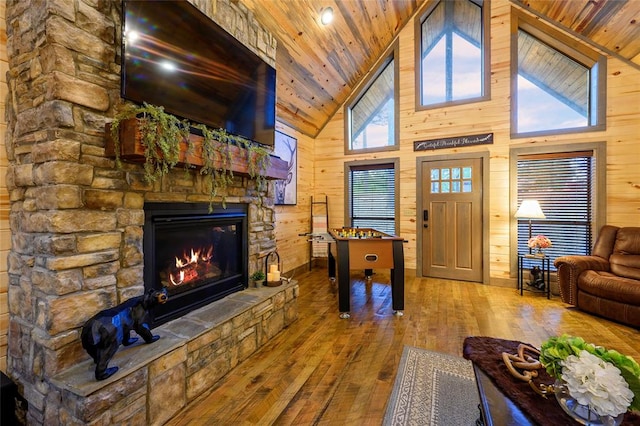 living room with wood walls, a fireplace, high vaulted ceiling, and wooden ceiling