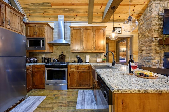 kitchen with pendant lighting, wall chimney exhaust hood, light stone counters, dark hardwood / wood-style flooring, and stainless steel appliances