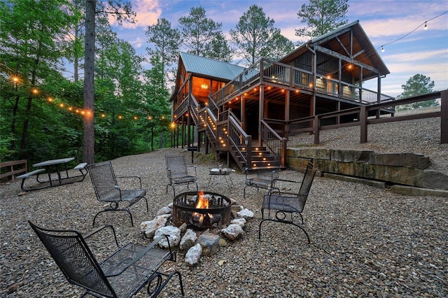 rear view of house with metal roof, stairs, a fire pit, and a deck